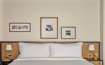 King bed centered in room with bedside tables, framed artwork, and neutral tones creating a calm space at Romer House Waikiki.