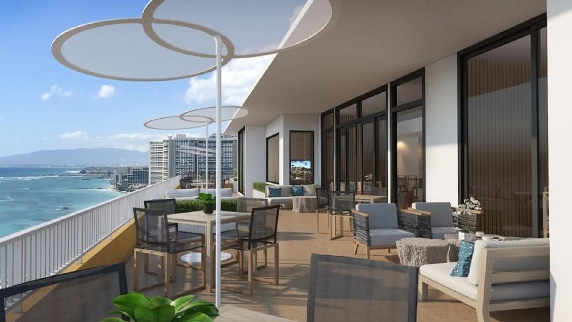 Large terrace with dining tables, lounge seating, and panoramic oceanfront views at The Twin Fin Hotel.