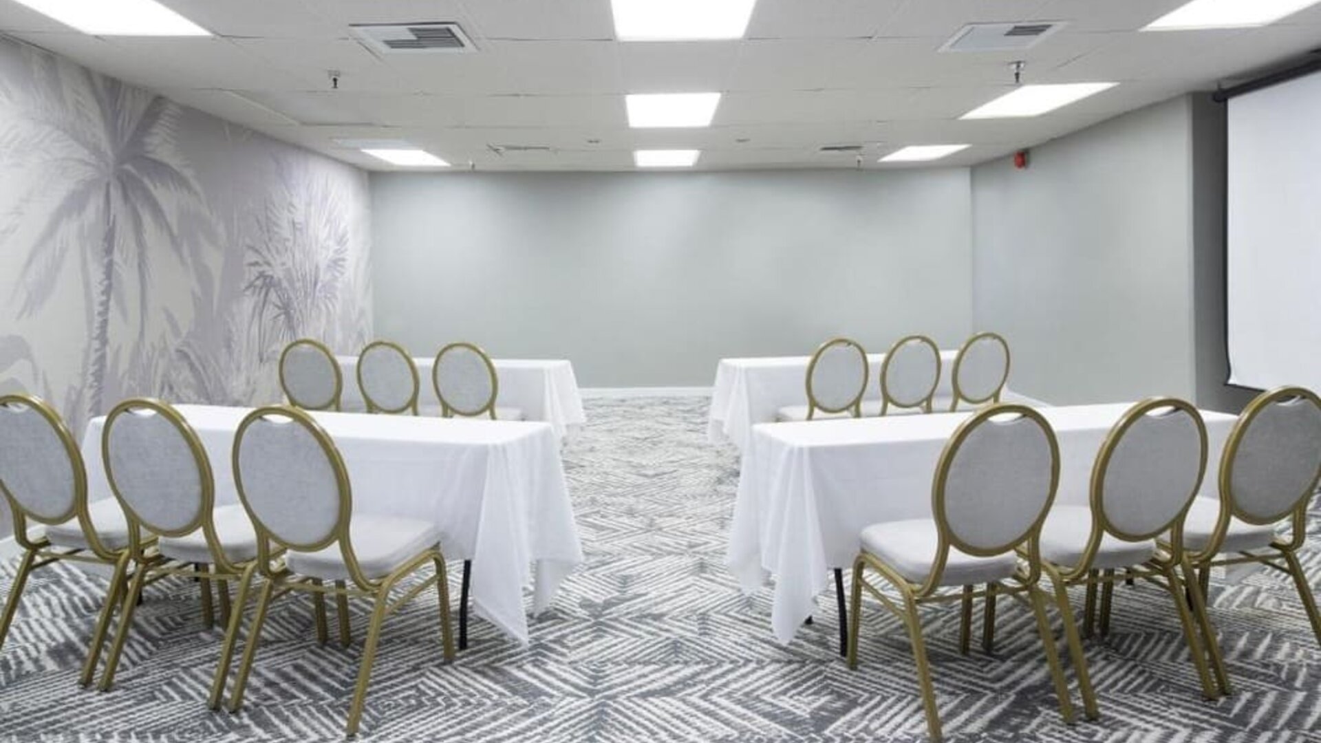 Meeting room with round-backed chairs, white tablecloths, and patterned carpet at The Twin Fin Hotel.