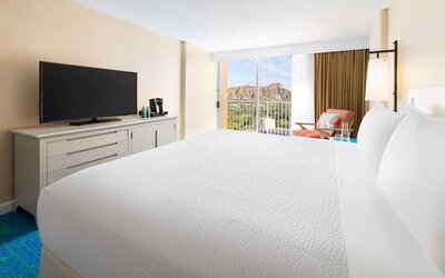 Close view of king bed facing balcony with mountain view at The Twin Fin Hotel.