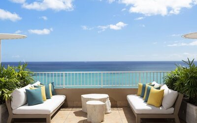 Outdoor seating area with ocean view, cushioned sofas, and umbrellas at The Twin Fin Hotel.
