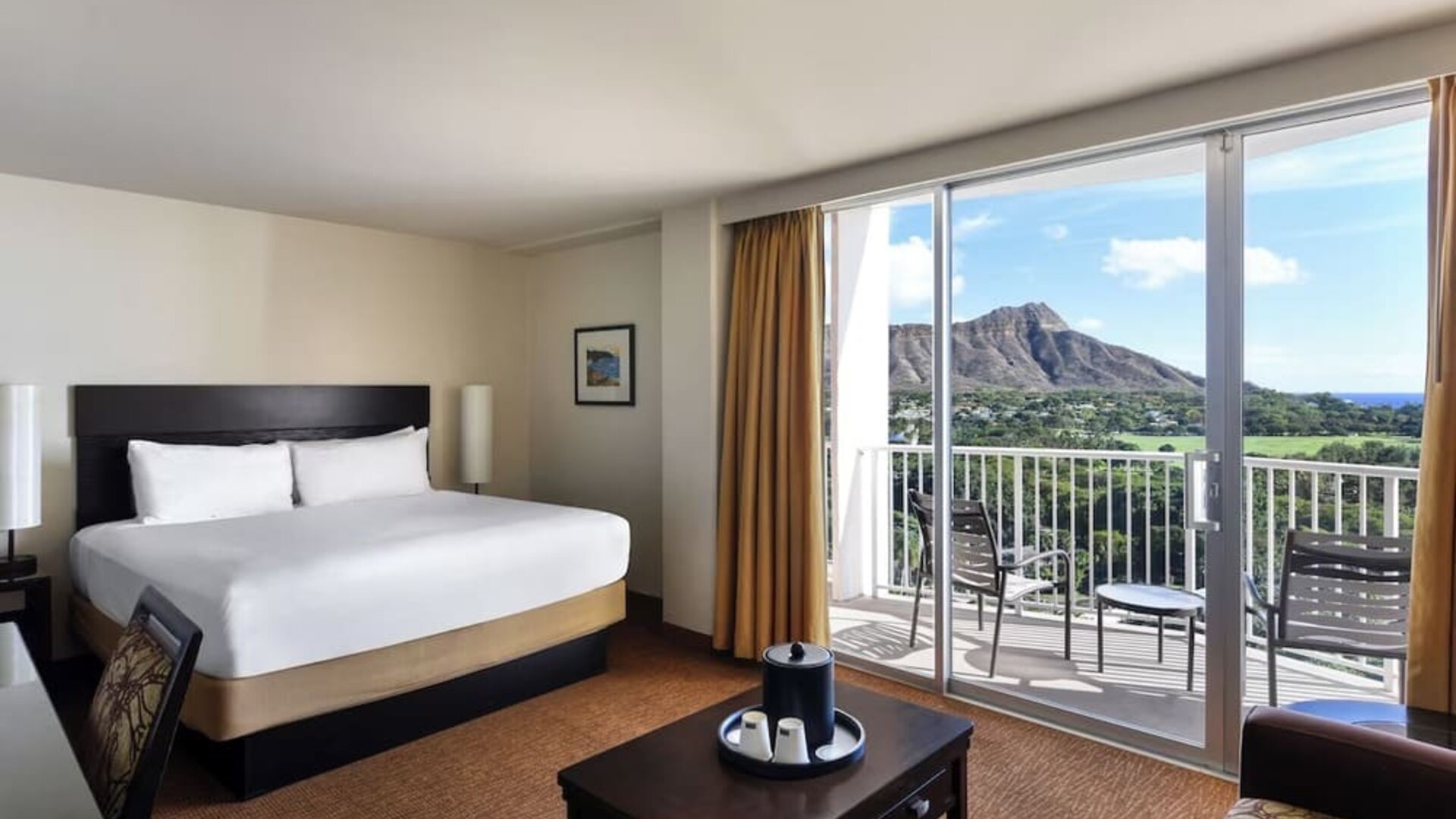 King bed room with balcony view of mountain and surrounding greenery at Park Shore Waikiki.