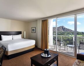King bed room with balcony view of mountain and surrounding greenery at Park Shore Waikiki.