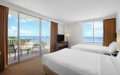 Room with two double beds, large windows, balcony, and ocean views at Park Shore Waikiki.