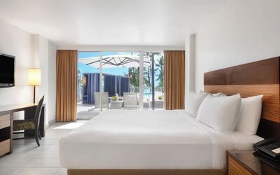 King bed room with desk, TV, and sliding doors opening to a patio with seating at Park Shore Waikiki.