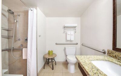Accessible bathroom with walk-in shower, grab bars, toilet, and granite vanity at Park Shore Waikiki.
