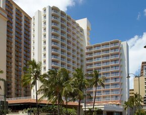Exterior view of Park Shore Waikiki hotel building with balconies and palm trees in front.