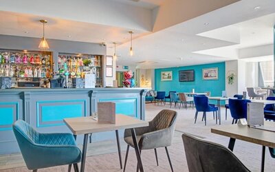 Stylish dining and bar area with blue accents, upholstered chairs, and pendant lighting at Atlantic Tower Hotel Liverpool By Sunday.
