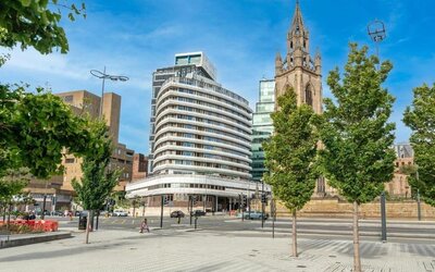 Exterior view of hotel building near historic church and city street at Atlantic Tower Hotel Liverpool By Sunday.