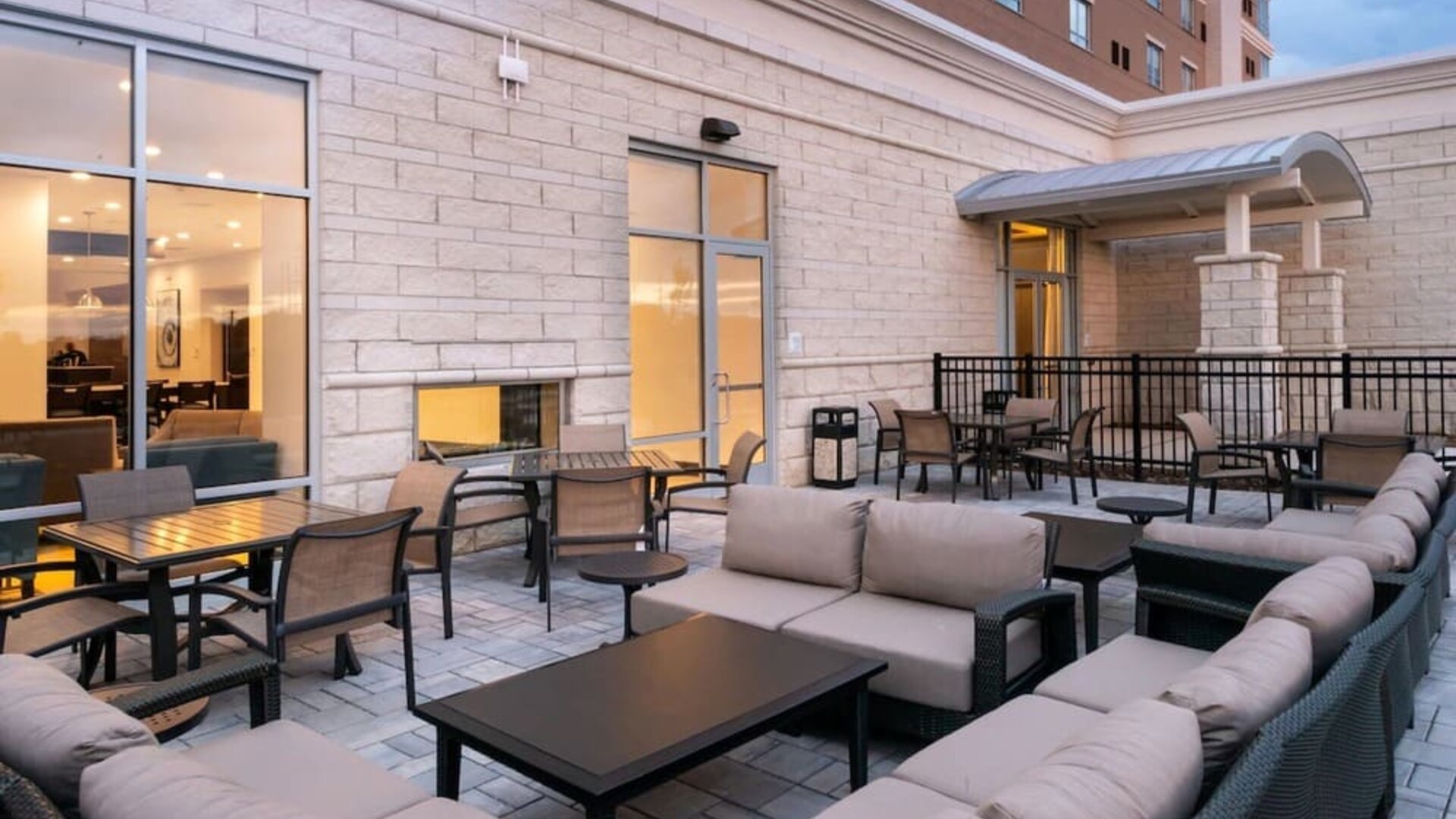 Outdoor seating area with cushioned sofas, tables, and covered entrance at Holiday Inn & Suites Farmington Hills - Detroit NW By IHG.