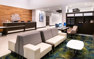 Lobby with front desk, seating area, patterned carpet, and modern decor at Holiday Inn & Suites Farmington Hills - Detroit NW By IHG.