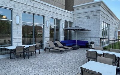 Outdoor patio with lounge chairs, umbrella seating, and paved terrace at Holiday Inn & Suites Farmington Hills - Detroit NW By IHG.