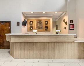 Reception desk with light wood finish, wall decor, and check-in computers at Comfort Suites Bush Intercontinental Airport.