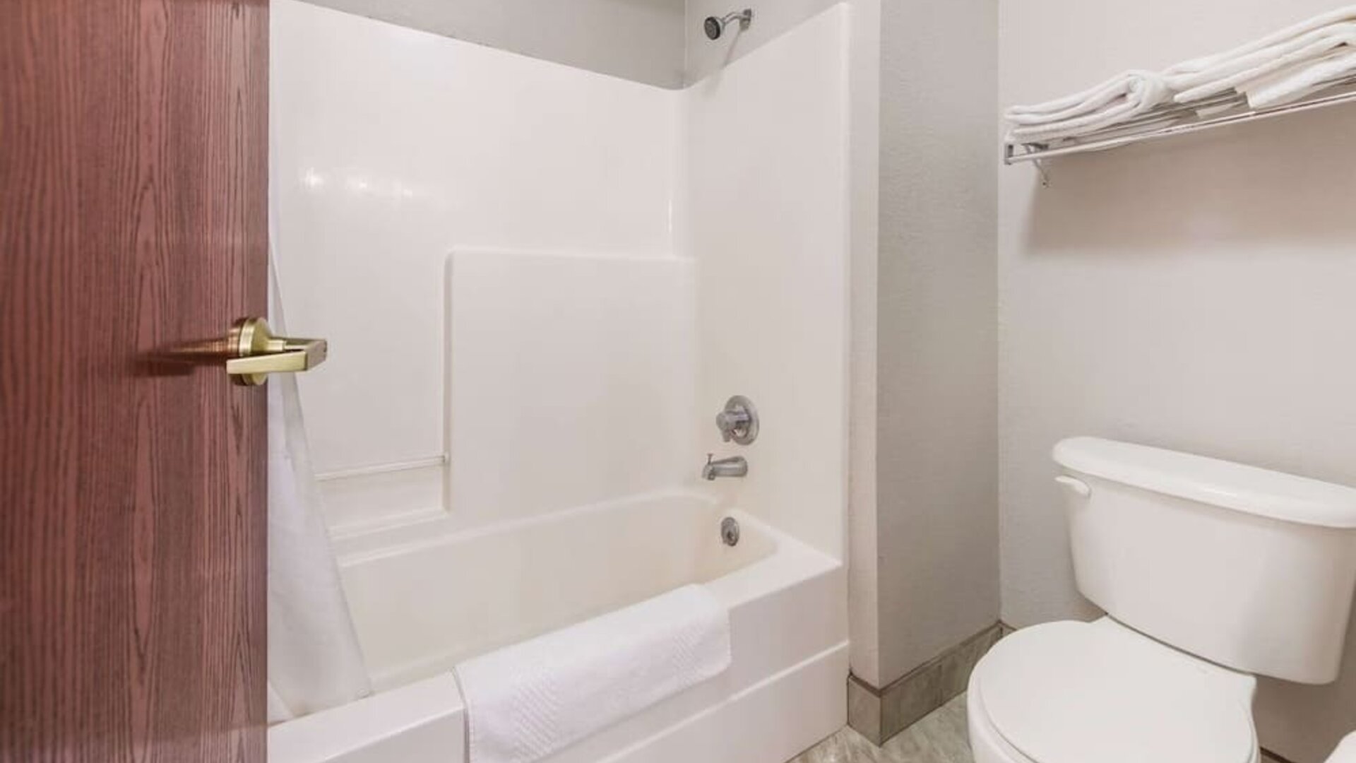Bathroom with bathtub shower combo, toilet, towel rack, and tiled floor at Suburban Studios Mason Hwy-42.