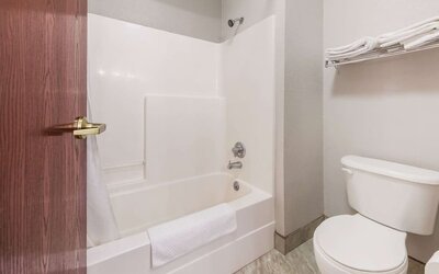 Bathroom with bathtub shower combo, toilet, towel rack, and tiled floor at Suburban Studios Mason Hwy-42.