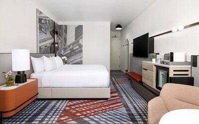 Guest room with king bed, mini fridge, coffee station, wall art, and modern furnishings at M Social New York Downtown.