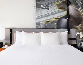 Close-up of king bed with plush pillows, bedside tables, and modern wall art at M Social New York Downtown.
