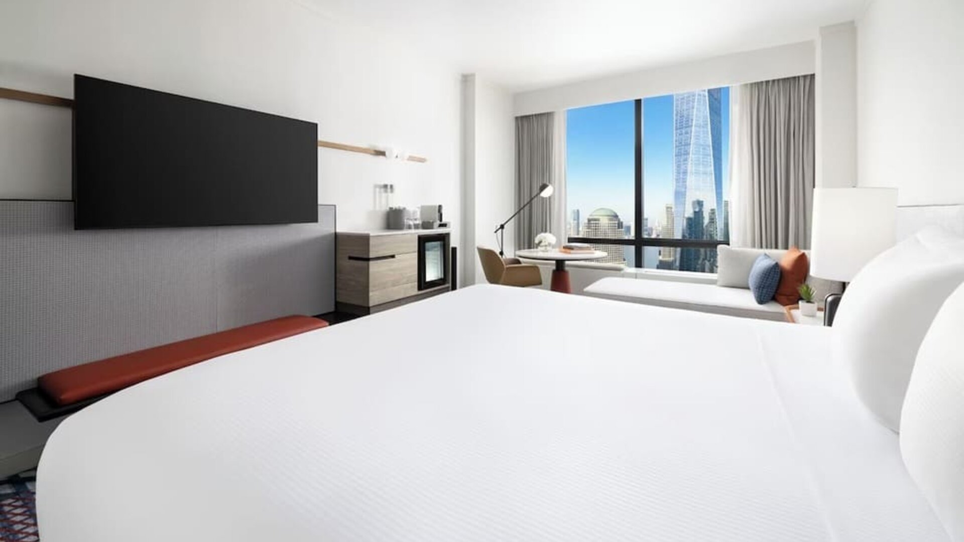 King room with large bed, wall-mounted TV, workspace, and floor-to-ceiling window with city view at M Social New York Downtown.
