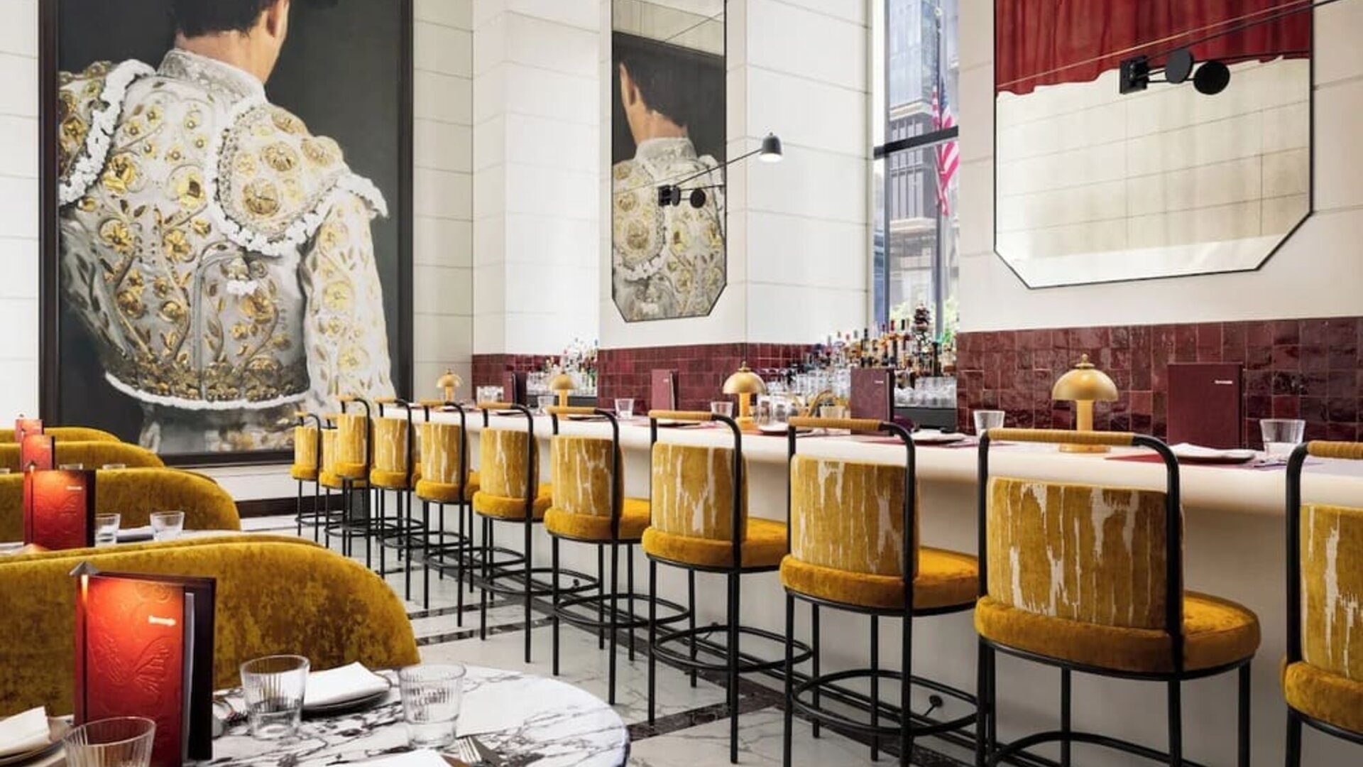 Restaurant bar area with high seating, decorative lighting, mirrors, and curated bar display at M Social New York Downtown.