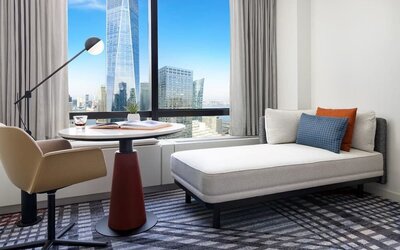 Seating area with chaise lounge, table, and floor-to-ceiling window showcasing city views at M Social New York Downtown.