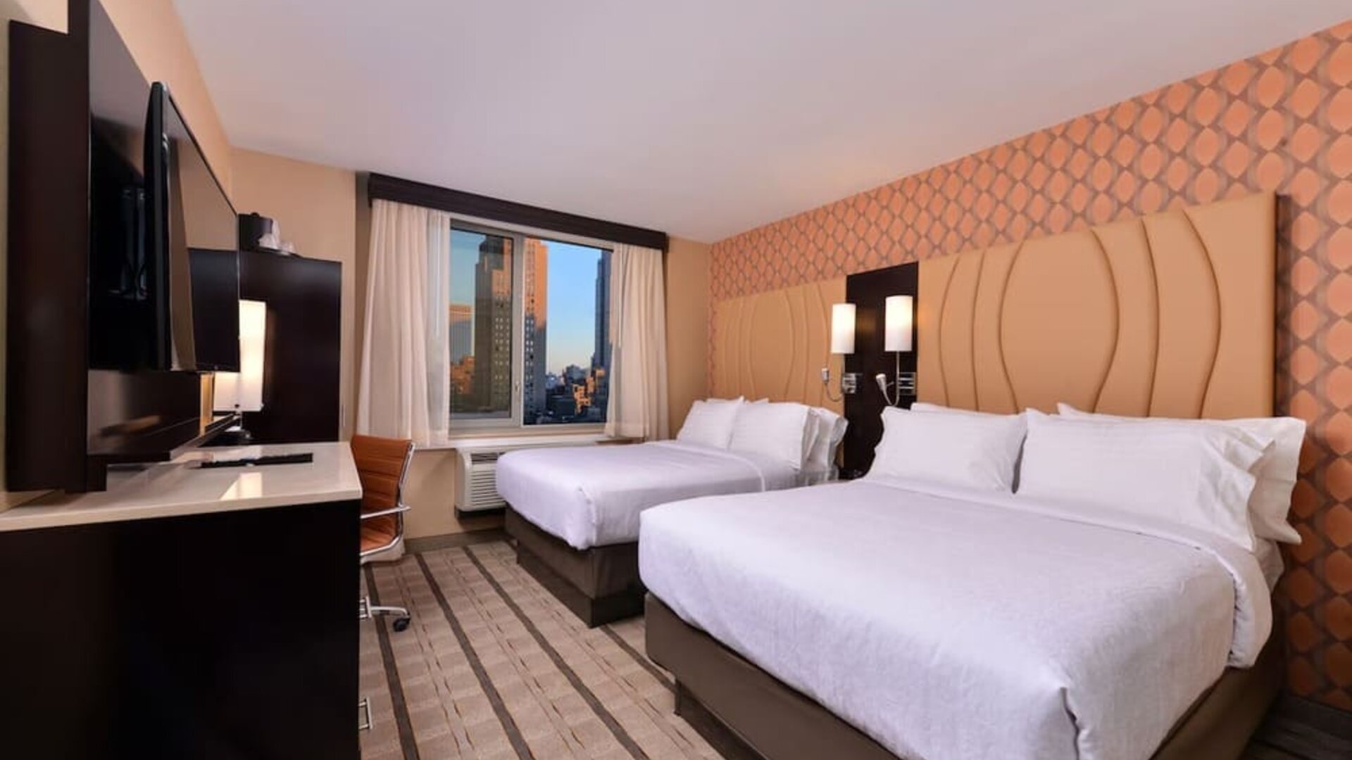 Guest room with two double beds, modern furnishings, and city view window at Holiday Inn New York City - Times Square By IHG.
