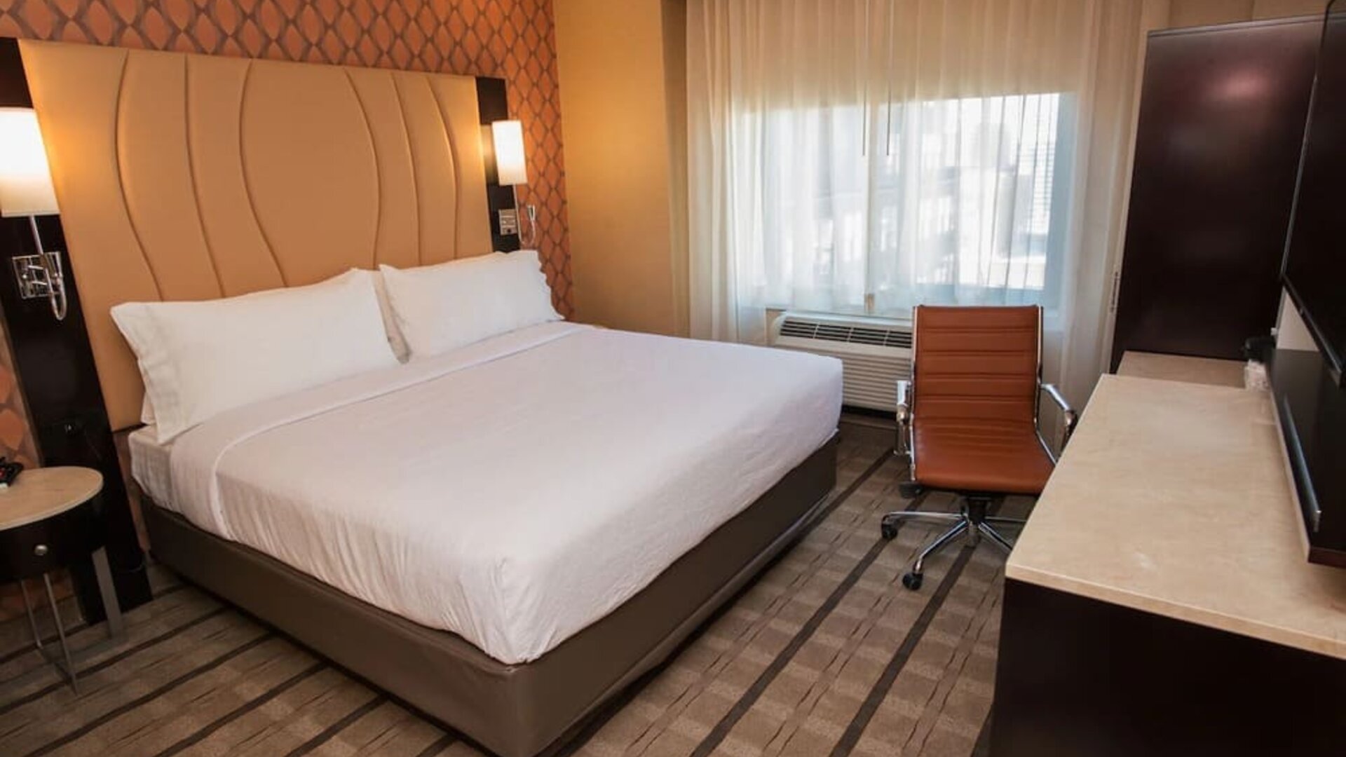 Guest room with king bed, workspace desk, chair, and window with natural light at Holiday Inn New York City - Times Square By IHG.