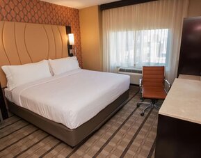 Guest room with king bed, workspace desk, chair, and window with natural light at Holiday Inn New York City - Times Square By IHG.