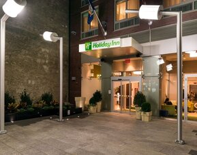 Hotel front entrance with illuminated signage and glass doors at Holiday Inn New York City - Times Square By IHG.