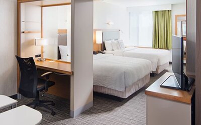Guest room with two double beds, workspace desk, chair, and television area at Springhill Suites Carle Place.
