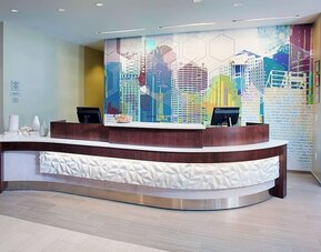 Reception desk area with modern design and colorful wall art at Springhill Suites Carle Place.