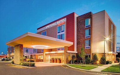 Exterior view of the hotel building with covered entrance and landscaping at Springhill Suites Carle Place.