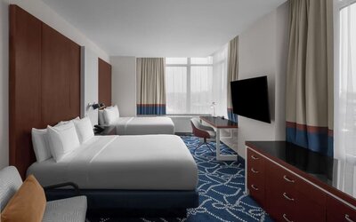 Guest room with two double beds, workspace desk, chair, and large windows at Hilton Brooklyn New York.