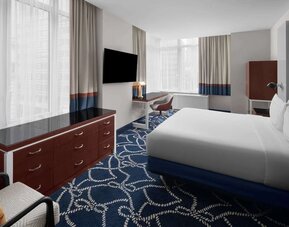 Guest room with king bed, workspace desk, chair, and large windows at Hilton Brooklyn New York.