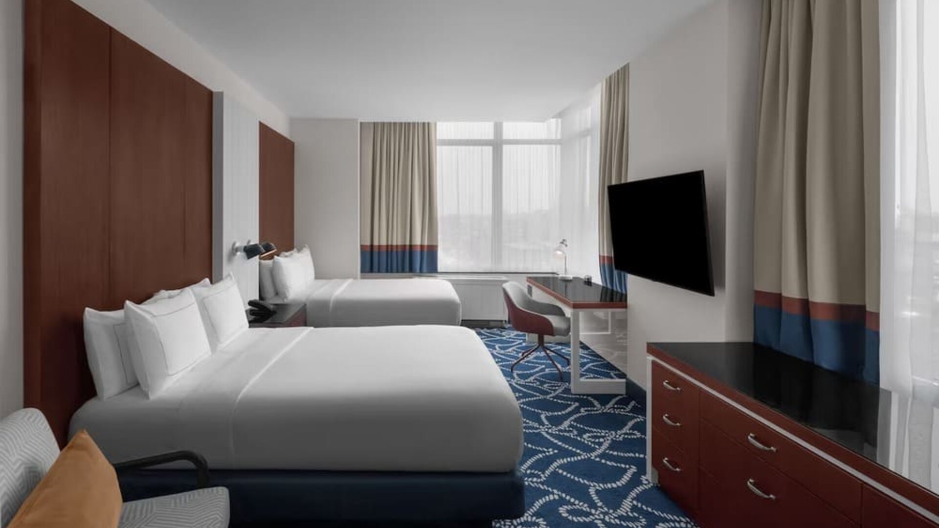 Guest room with two double beds, workspace desk, chair, and large windows at Hilton Brooklyn New York.