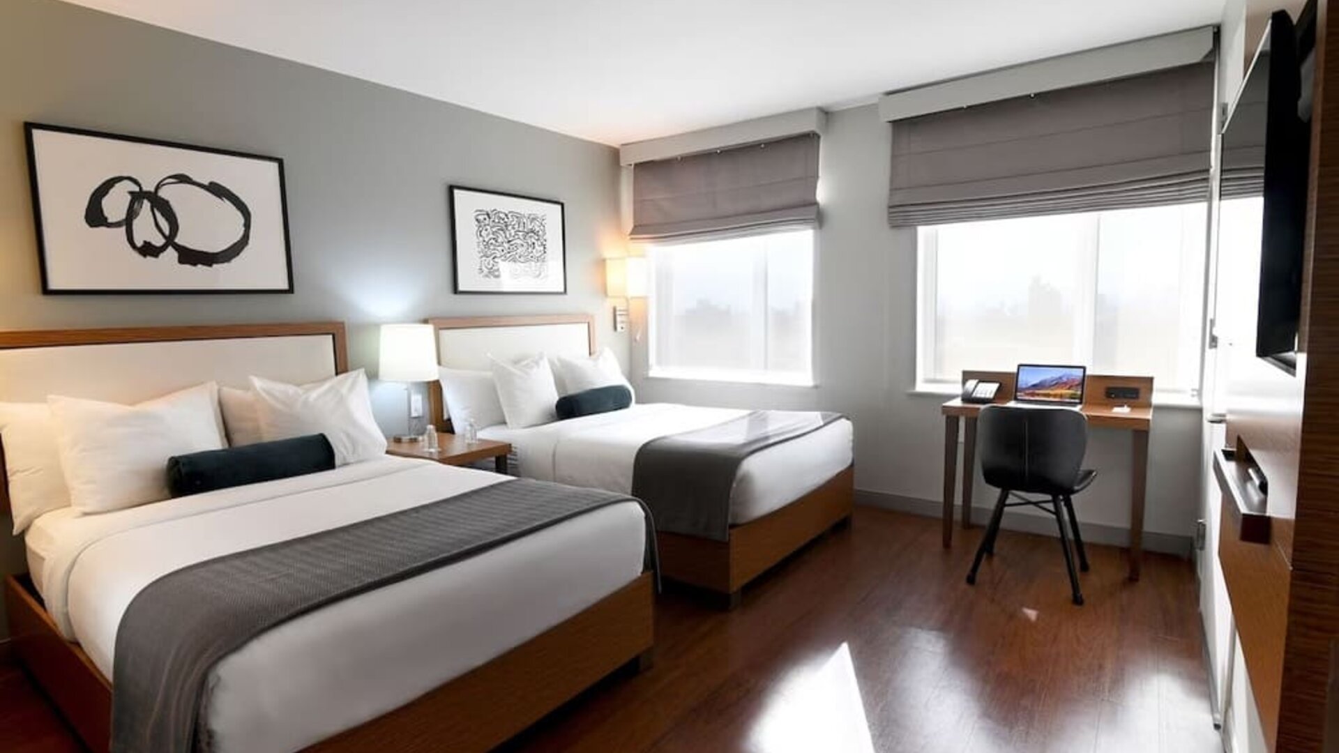 Guest room with two double beds, workspace desk, chair, and large windows at Edge Hotel NYC.