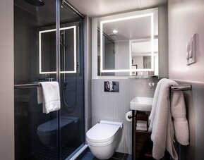 Bathroom with glass-enclosed shower, sink, mirror, and towels at La Quinta Times Square South.