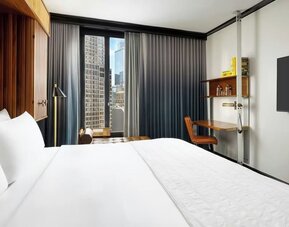 Guest room with king bed, workspace desk, and city view window at Le Méridien New York, Central Park.