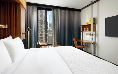 Guest room with king bed, workspace desk, and city view window at Le Méridien New York, Central Park.