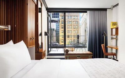 Guest room with king bed, workspace, and balcony access with city views at Le Méridien New York, Central Park.