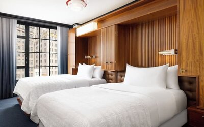 Guest room with two double beds, wood-paneled headboard, and large windows at Le Méridien New York, Central Park.