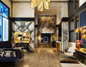 Hotel lobby with high ceilings, marble walls, seating area, and modern décor at Le Méridien New York, Central Park.
