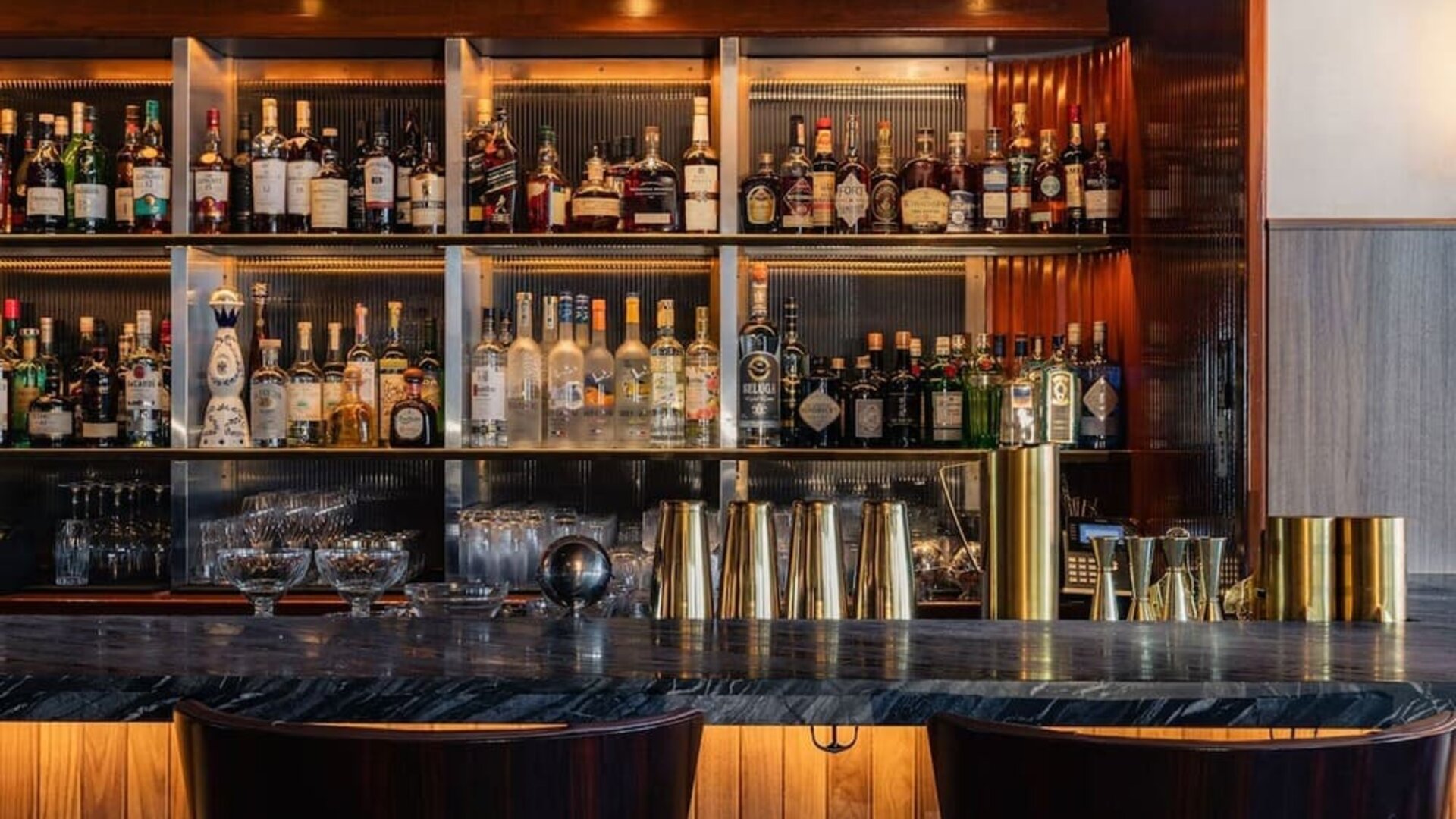 Bar area with shelves of liquor, counter seating, and warm lighting at Le Méridien New York, Central Park.