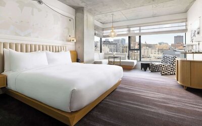 Spacious king room with large bed, modern décor, and city skyline views at Timbri Hotel San Francisco, Curio Collection By Hilton.