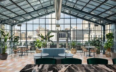 Bright indoor dining space with large glass ceiling, greenery, and city views at Timbri Hotel San Francisco, Curio Collection By Hilton
