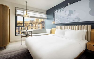 Modern bedroom with large bed, accent wall, and city view seating area at Timbri Hotel San Francisco, Curio Collection By Hilton.