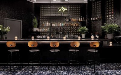 Elegant bar area with high stools, ambient lighting, and a curated selection of drinks at Timbri Hotel San Francisco, Curio Collection By Hilton.