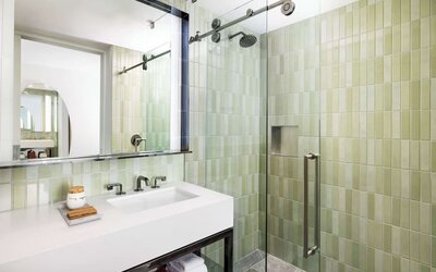 Modern bathroom with glass walk-in shower, green tile finish, and sleek vanity at Timbri Hotel San Francisco, Curio Collection By Hilton.