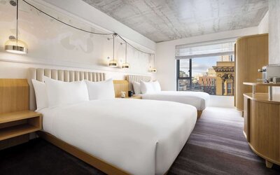 Stylish double room with two beds, warm lighting, contemporary décor, and city-facing window at Timbri Hotel San Francisco, Curio Collection By Hilton.