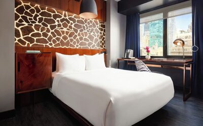 Stylish guest room with king bed, desk workspace, city views, and decorative feature wall at Hotel Hendricks.