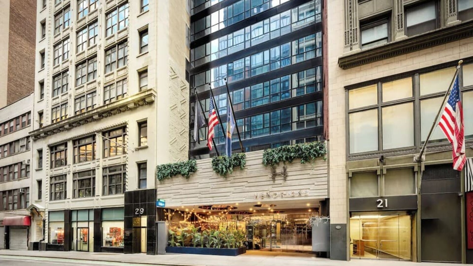 Hotel entrance with signage, greenery, and welcoming street-level access at Hotel Hendricks.